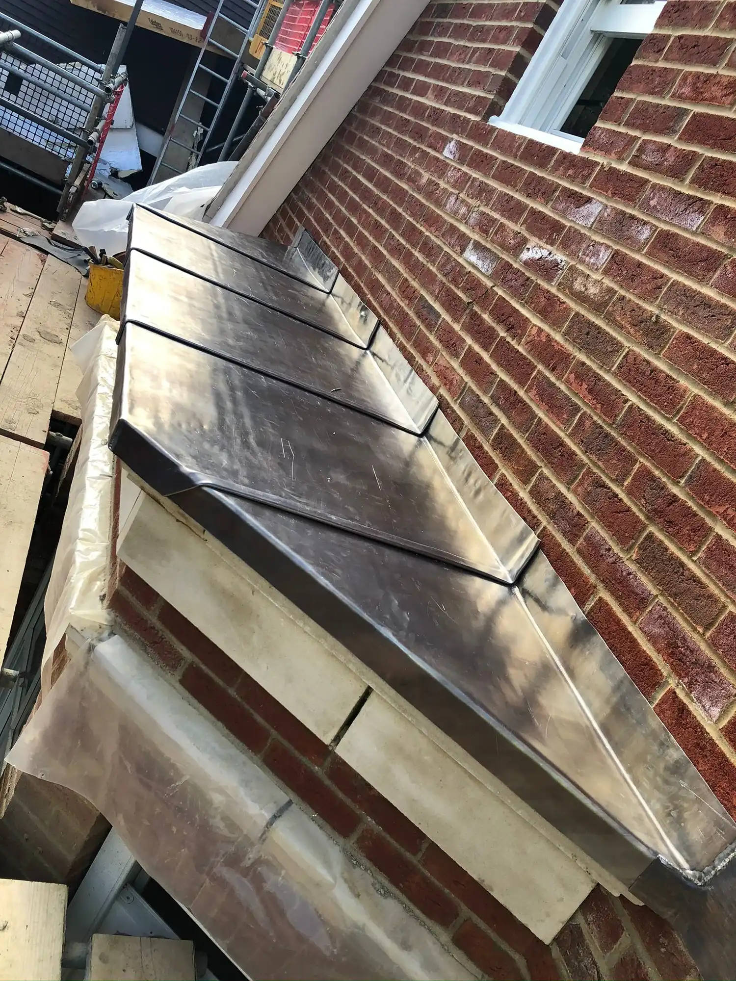 A metal gutter on the side of a brick building.