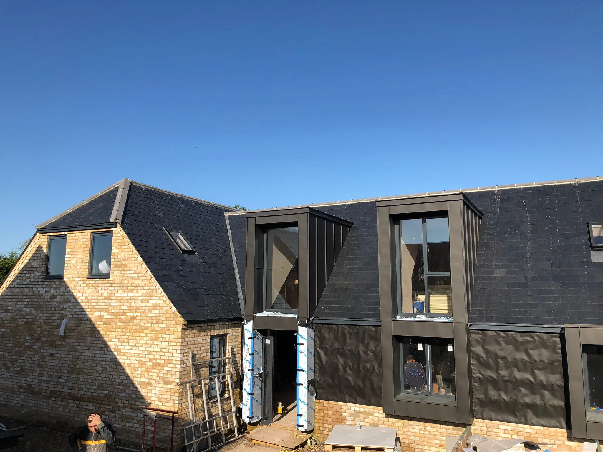 A couple of people standing outside of a house under construction.